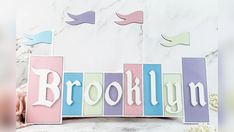 the name brooklyn is spelled with wooden blocks in pastel colors on a marble background