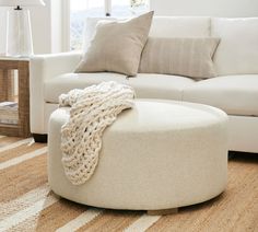 a white couch and ottoman in a living room with beige rugs on the floor