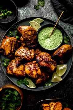 grilled chicken on a plate with green sauce and garnished with limes