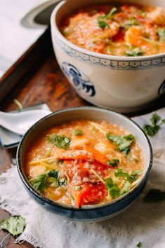 two bowls filled with soup on top of a wooden table