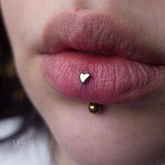 a woman's lips with a tiny gold heart on the lip