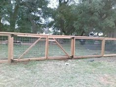 a wooden fence with wire around it in the middle of a yard next to trees