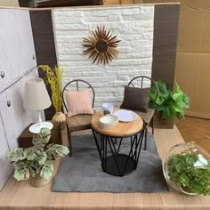 a table with two chairs and some plants in front of a white brick wall behind it