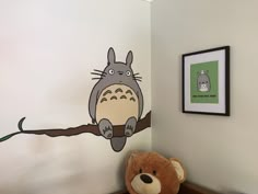 a brown teddy bear sitting on top of a wooden table next to a wall mural