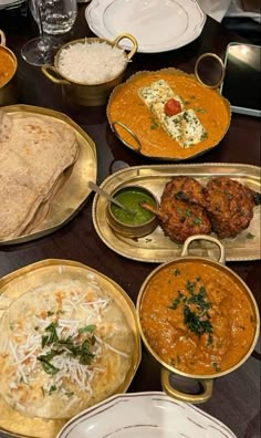 a table topped with lots of different types of food on plates and silver trays