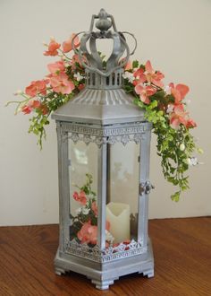 a metal lantern with flowers in it on a table