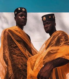 two black men dressed in yellow standing next to each other with their hands on their hips