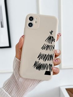 a woman holding up a phone case with a christmas tree on it