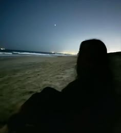 a person is sitting on the beach at night