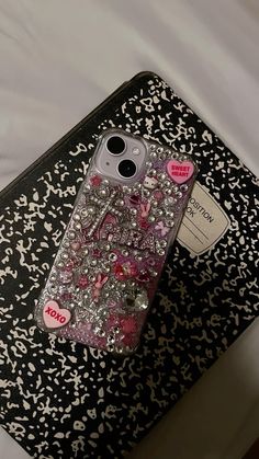 a cell phone case sitting on top of a black and white cover with pink hearts