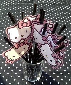 hello kitty cupcake toppers in a vase on a polka dot tablecloth with black straws