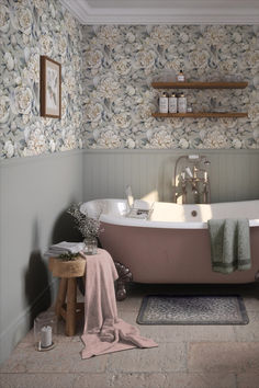 a bath tub sitting next to a wooden stool in a bathroom with floral wallpaper