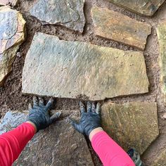 two people standing on top of a stone floor next to rocks and dirt with their hands in the ground