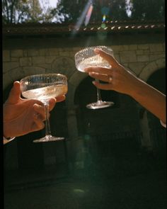 two people holding wine glasses in their hands