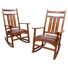 two wooden rocking chairs with brown leather seats