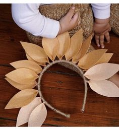 a child's hand is touching the top of a wreath made out of paper leaves