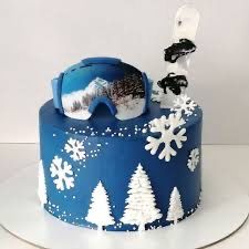 a blue cake with white snowflakes and trees on the top is decorated in frosting