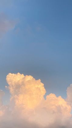 the airplane is flying high in the sky with clouds behind it and one plane on the ground