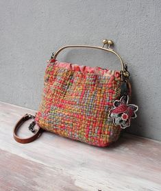 a small purse sitting on top of a wooden table next to a wall with a keychain hanging from it