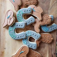 decorated cookies are arranged on a cutting board with blue and brown icing in the shape of cowboy boots