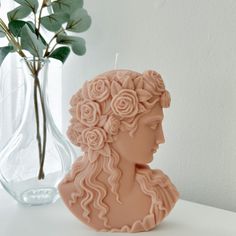 a candle that is sitting on a table next to a vase with flowers in it