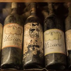 old wine bottles are lined up on a shelf