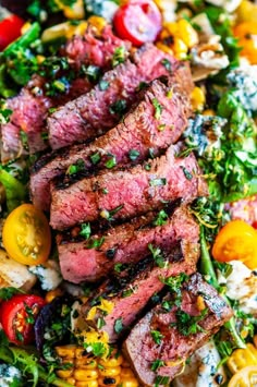 steak salad with tomatoes, corn, and herbs on a white platter topped with feta cheese