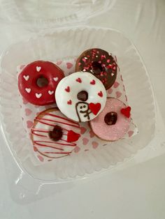 there are many different donuts on the plate in the tray, including one with heart shaped frosting and one with sprinkles