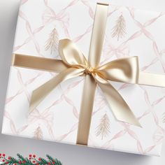 a christmas present wrapped in white paper with gold ribbon