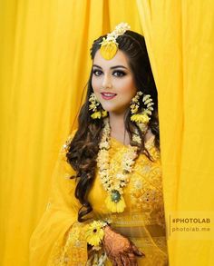 a woman in yellow dress with flowers on her head and hands, posing for the camera