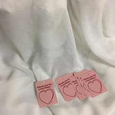 two pieces of pink paper with hearts cut out of them sitting on a white sheet