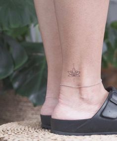 a woman's foot with a small flower tattoo on her left ankle and a chain around the ankle