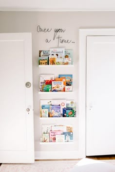 there is a white book shelf with books on it in the corner next to two doors