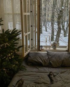 a bed sitting in front of a window next to a christmas tree with lights on it