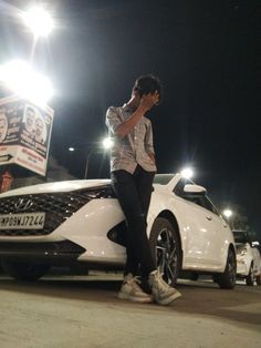 a man sitting on the hood of a white car