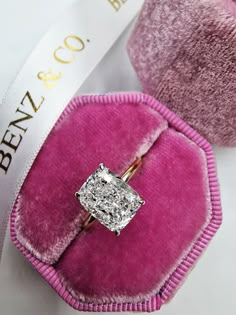 an engagement ring in a pink velvet case with a white ribbon around it and the words ben & co on top