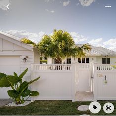 a white house with palm trees in front of it and the number 12 on the fence