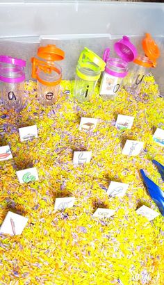 a bin filled with lots of yellow and purple confetti next to blue scissors