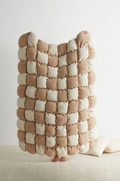 a cushion made out of pillows on top of a white surface with a person standing next to it