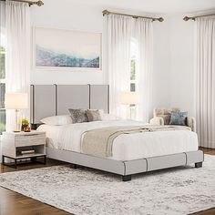 a white bedroom with a large bed and two night stands in front of the window