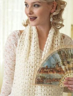 a woman wearing a white crochet scarf and holding a fan in her hand