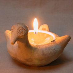 a small bird shaped candle holder with a lit candle