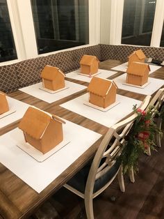 several gingerbread houses are sitting on top of white paper and placed on the table