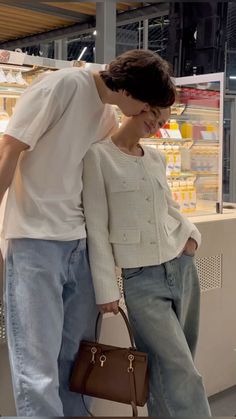 a man and woman standing next to each other in front of a store display case