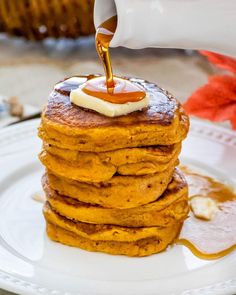 a stack of pancakes with syrup being poured on top