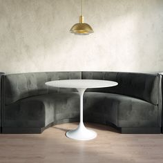 a white table sitting on top of a wooden floor next to a gray couch with a gold light hanging from the ceiling