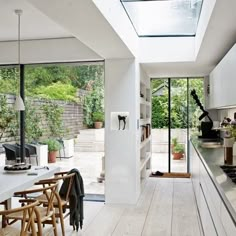 an open living room and dining area with large windows on both sides, white walls and wood flooring