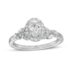 a white gold ring with an oval cut diamond surrounded by smaller round diamonds on the band