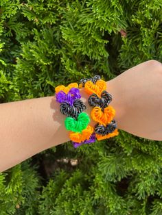 a person's arm with several bracelets made out of colorful crepe flowers