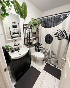 a bathroom with black and white decor on the shower curtain, rugs, and toilet